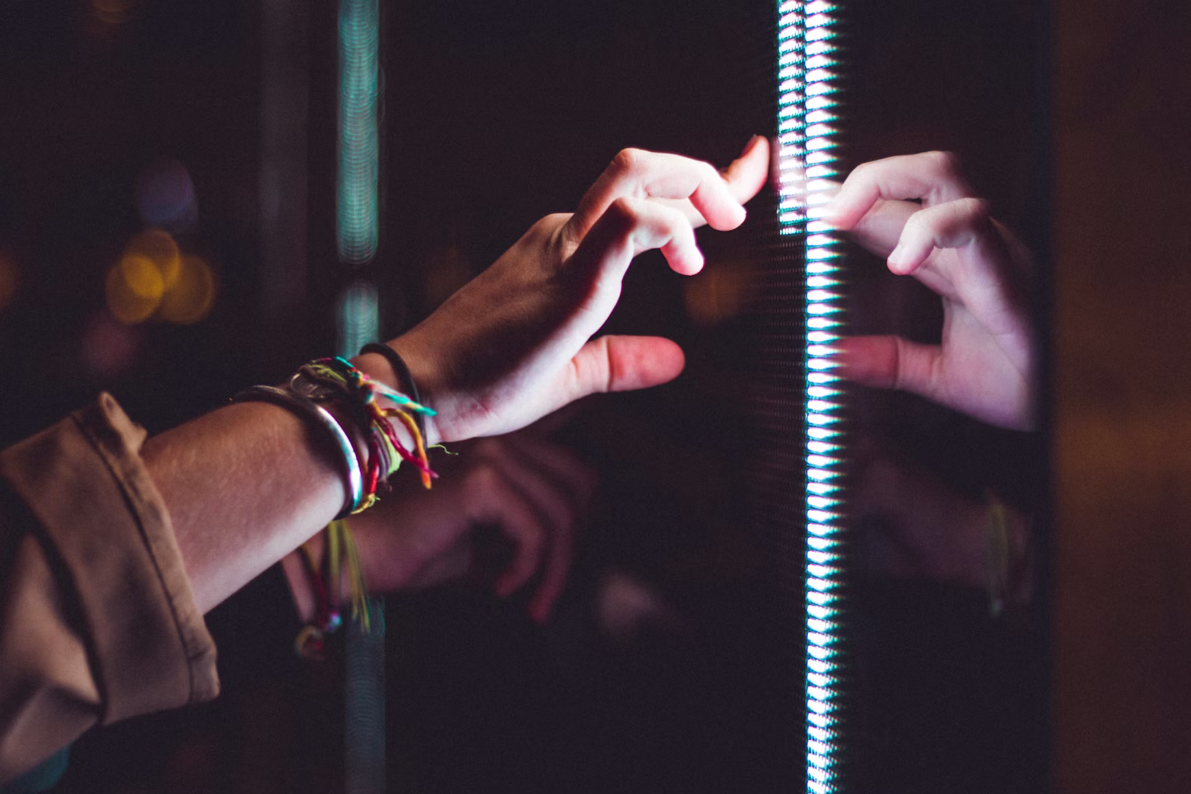 Hands meeting a vertical strip of light against a dark reflective surface — an interaction being tested.