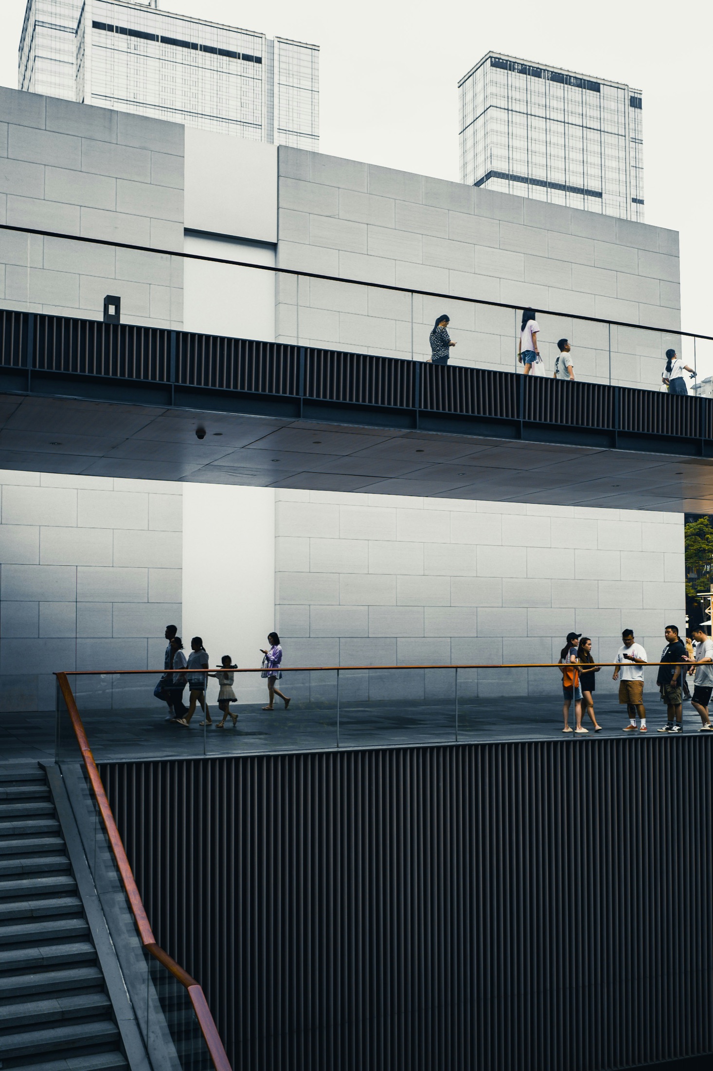People moving along the ramps and walkways of a crisp modern building in daylight.