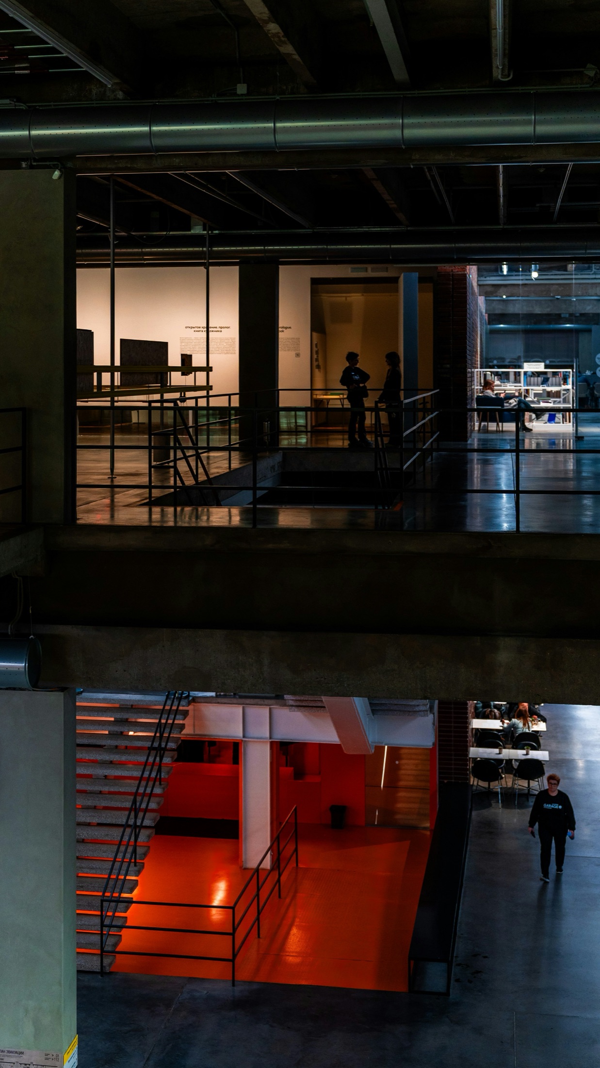 The working interior of a cultural building, an orange-lit stair glowing in the lower level.
