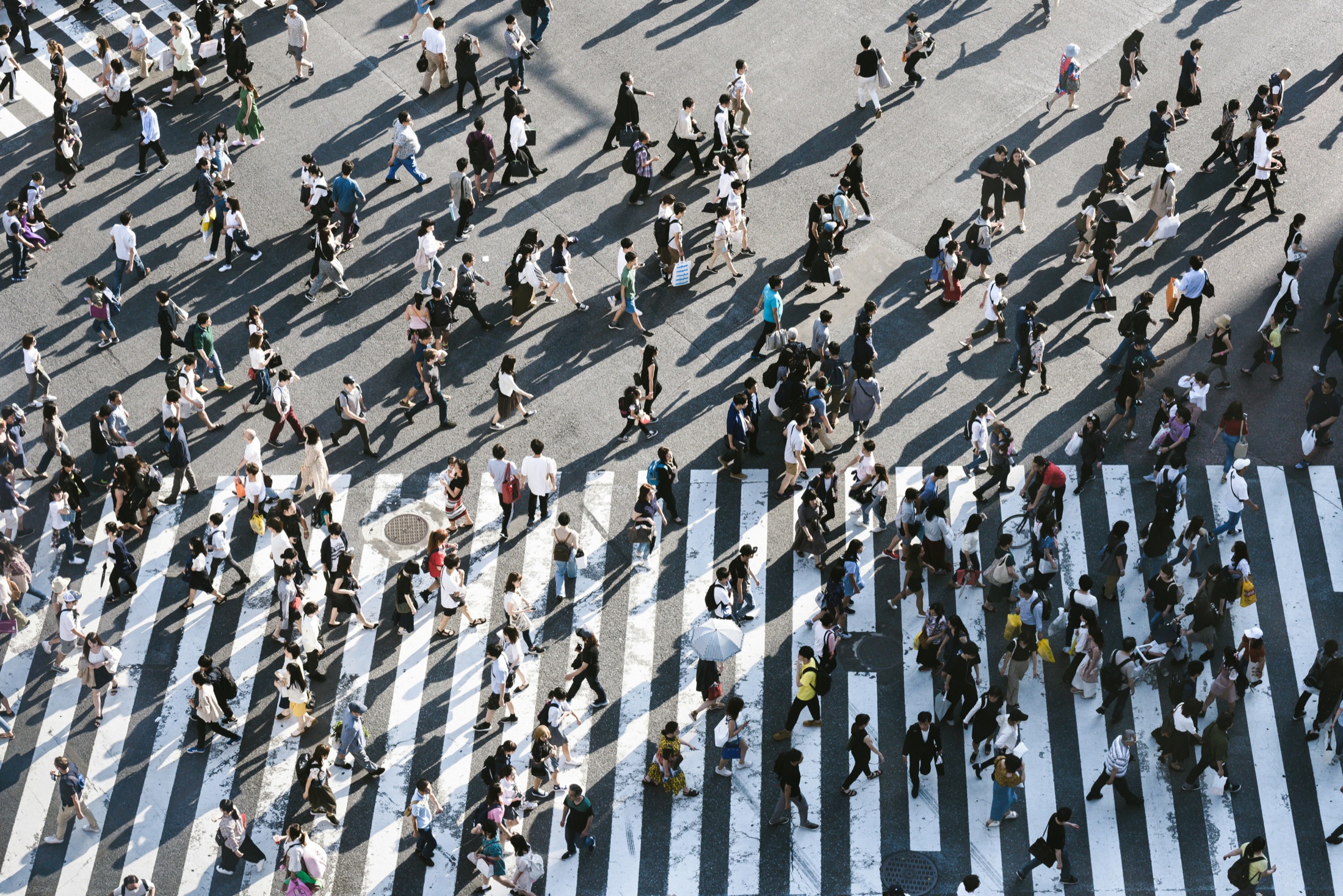 A crowded city crossing seen from above — streams of people moving across the painted lines.