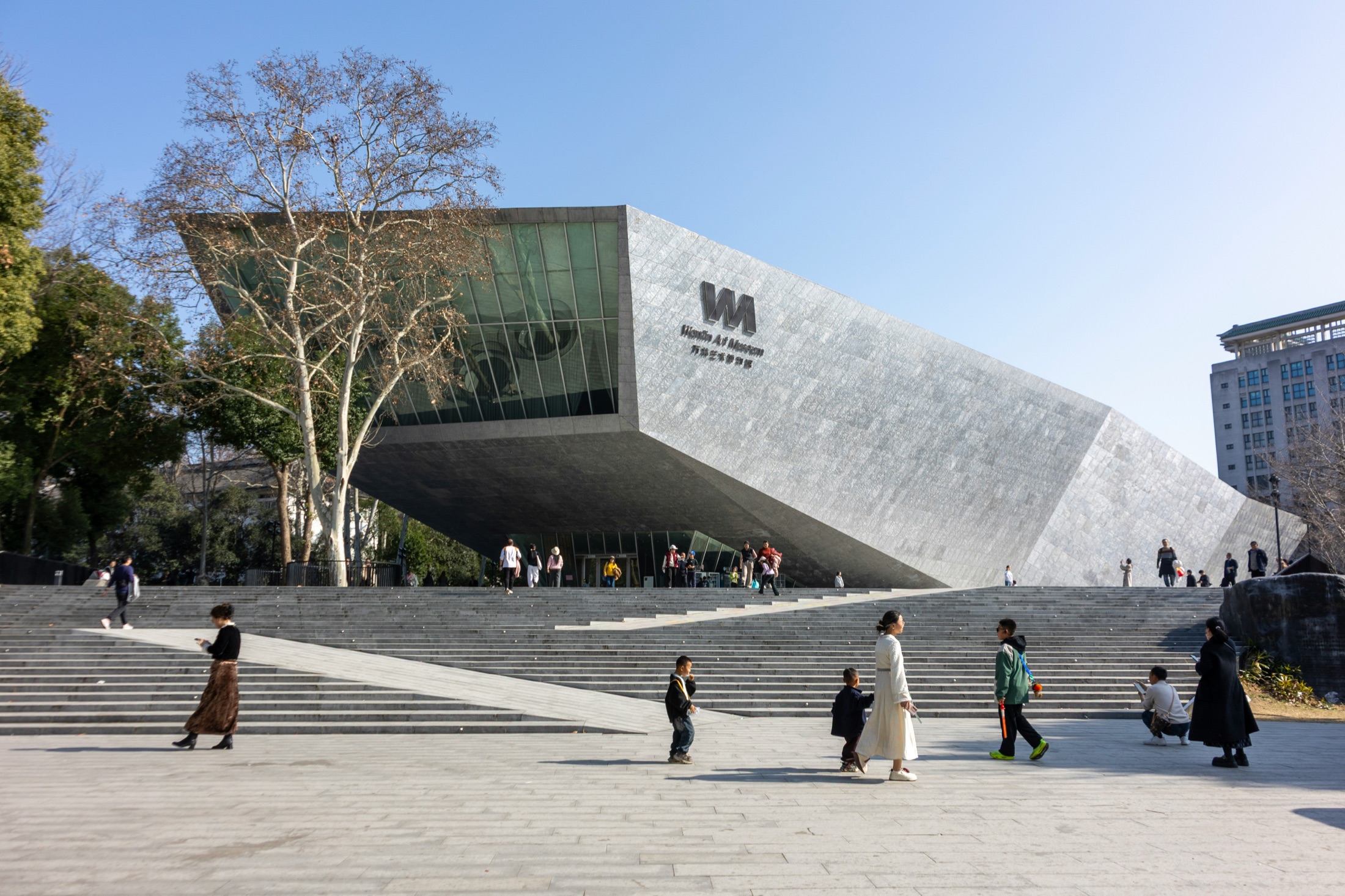 An angular stone museum above a broad public stair, visitors gathered across the steps.